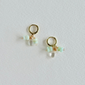Gold hoop earrings with clear and green beads on a light gray background