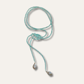 A turquoise beaded lariat necklace with two teardrop-shaped clear crystal pendants on a light beige background.