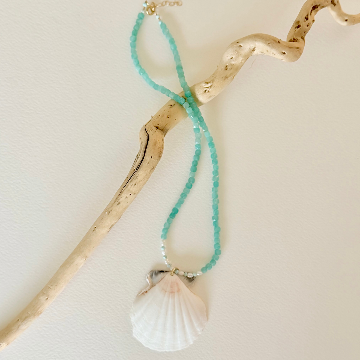 Necklace with turquoise beads and a shell pendant on a light background