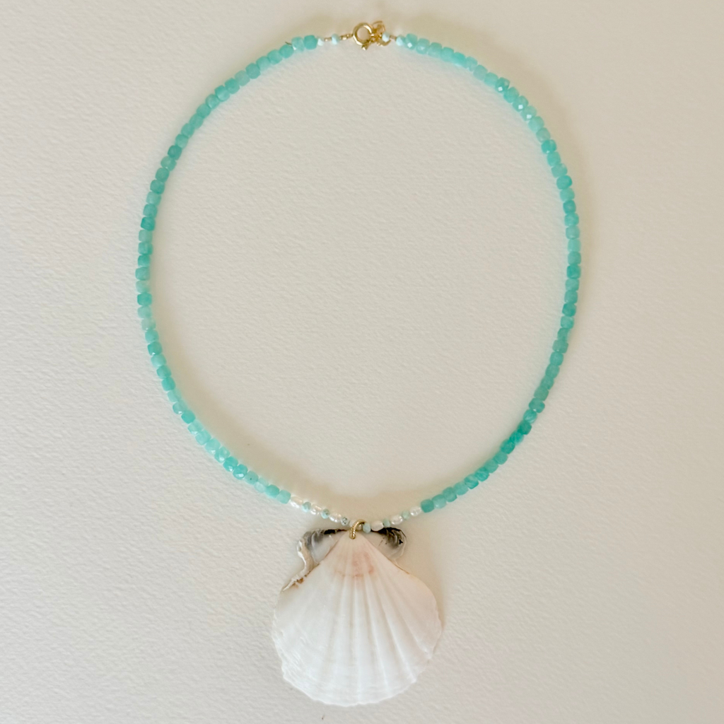 Necklace with turquoise beads and a shell pendant on a light background