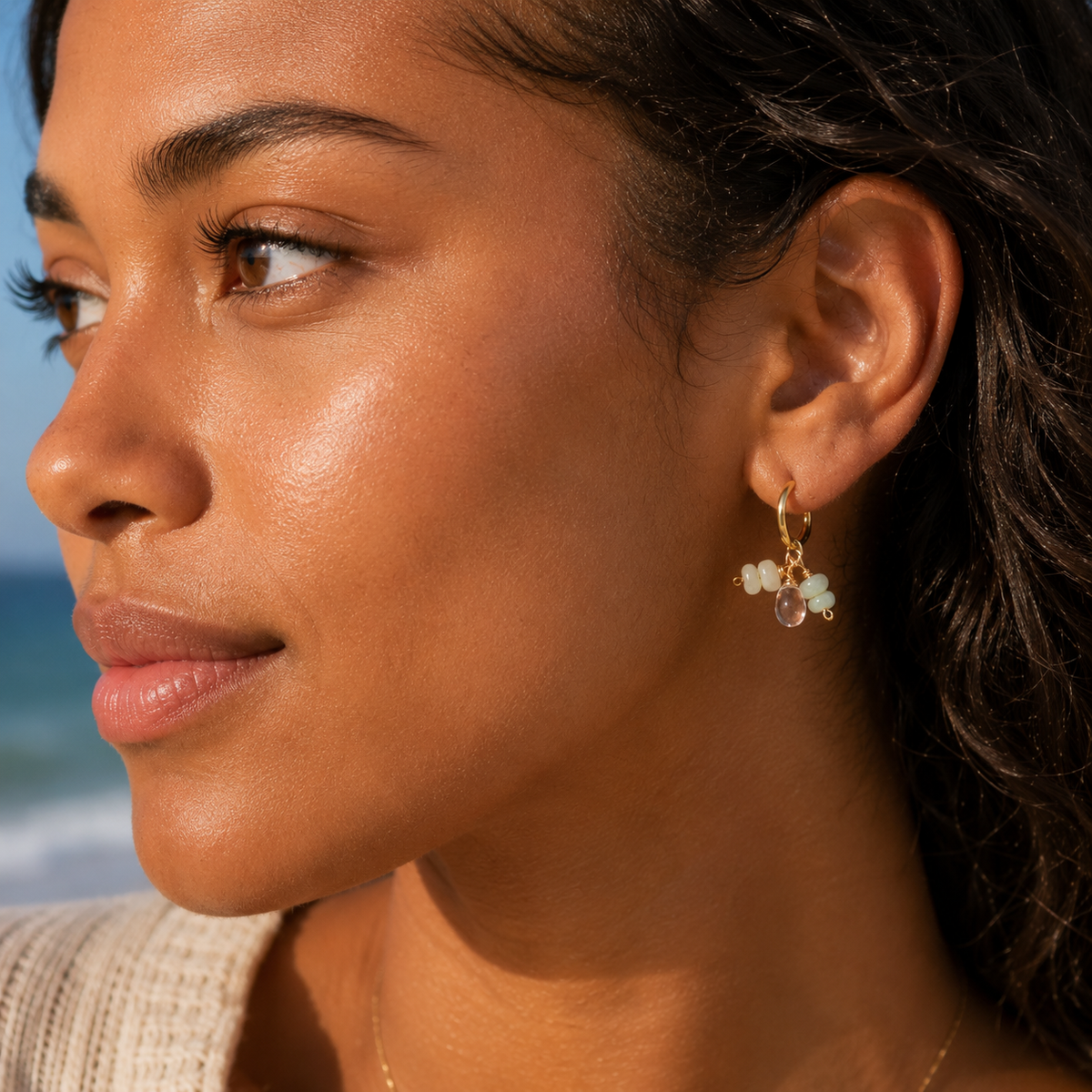 Close-up of a woman wearing earrings with a blurred beach background