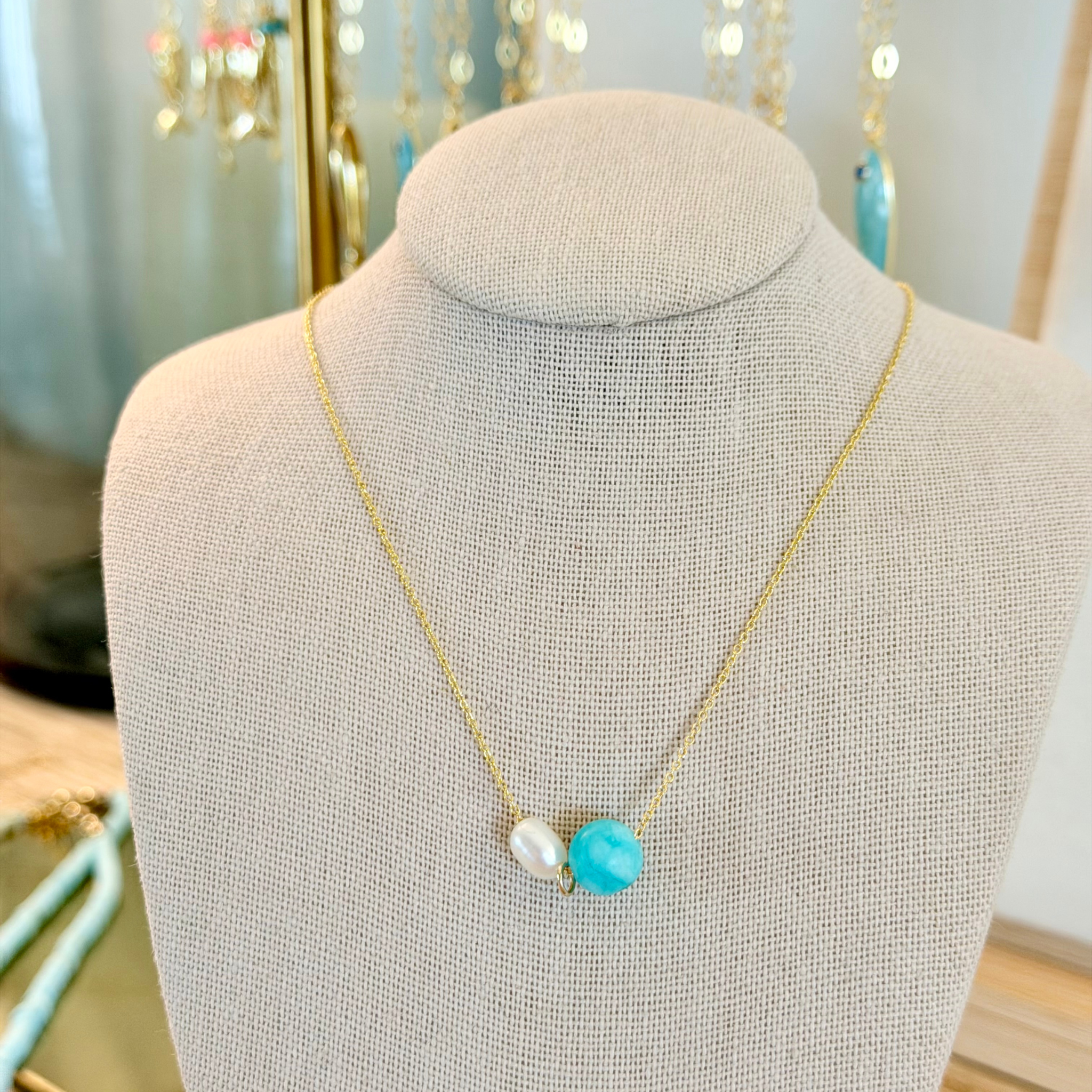 Necklace with turquoise and pearl pendant on a mannequin bust