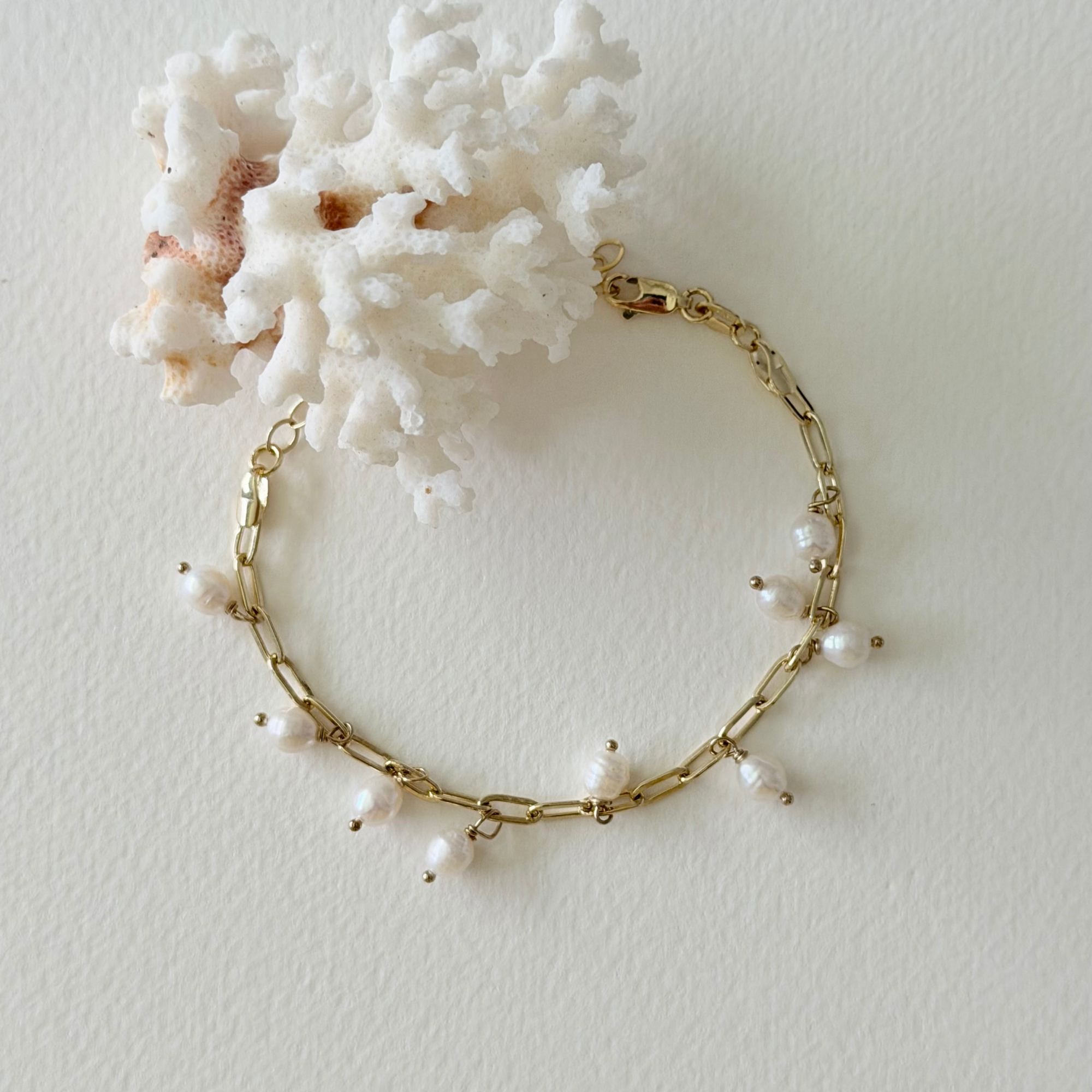 Gold bracelet with pearls on a white background