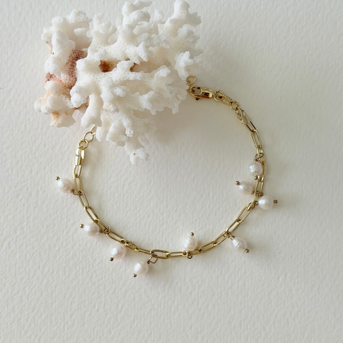 Gold bracelet with pearls on a white background