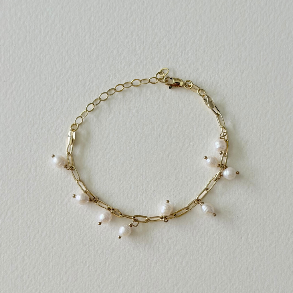 Gold bracelet with pearls on a light gray background