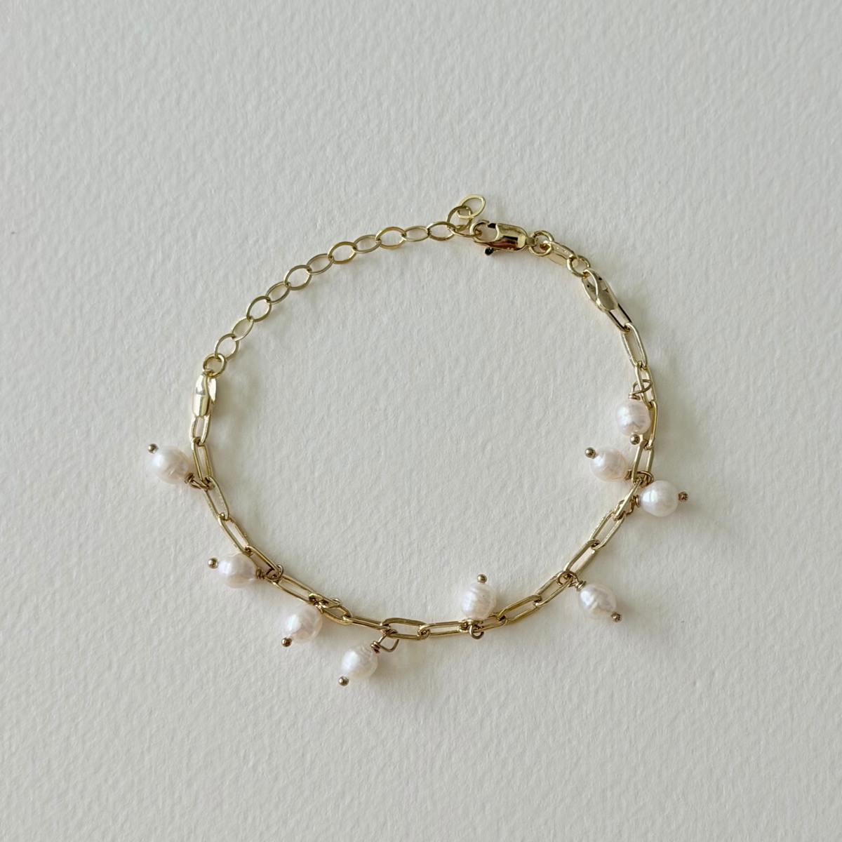 Gold bracelet with pearls on a light gray background