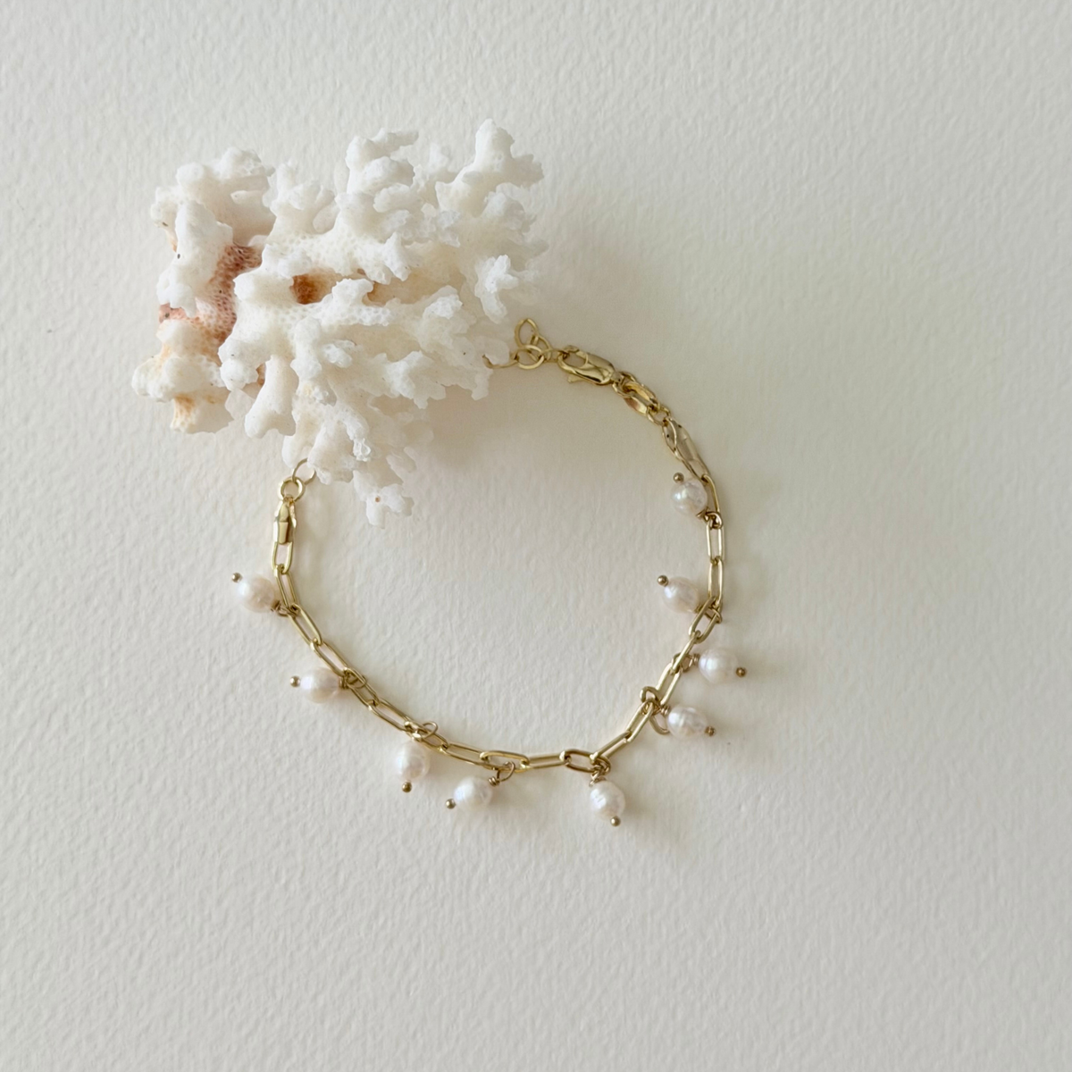Gold bracelet with pearls on a white background