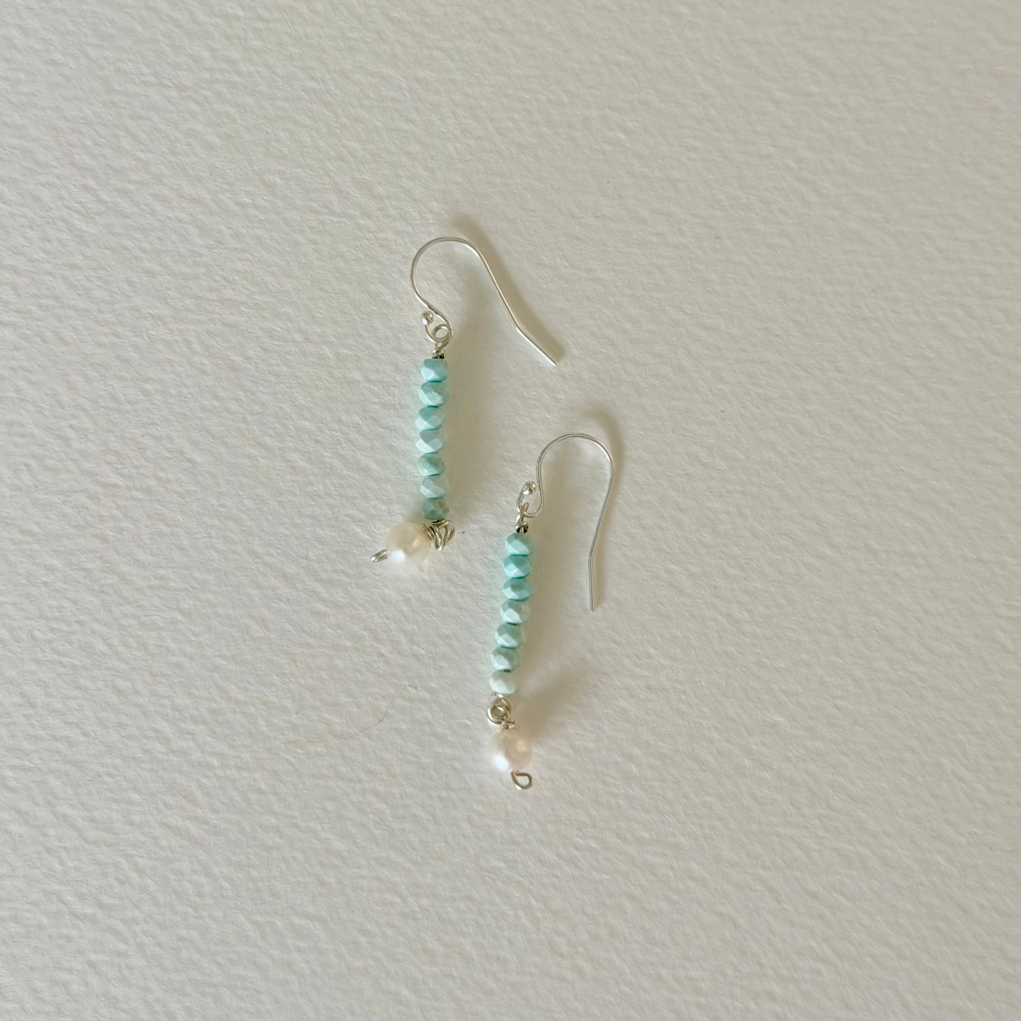 Pair of turquoise beaded earrings on a light gray background
