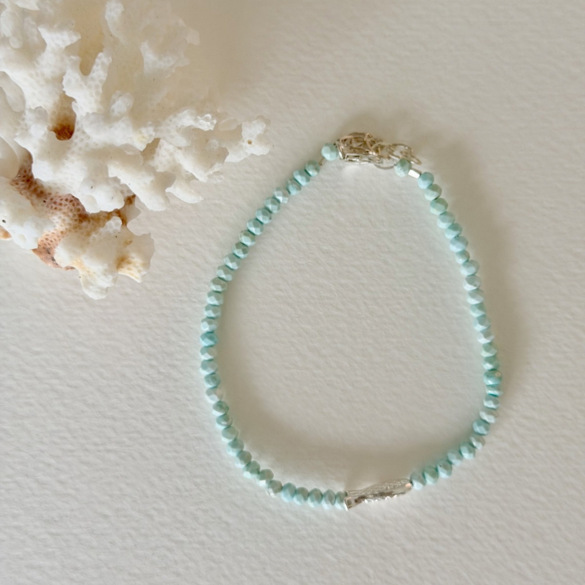 Turquoise beaded bracelet on a light background with coral