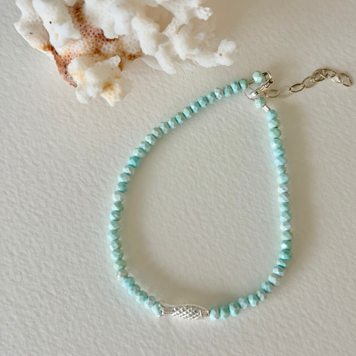Turquoise beaded bracelet with a silver clasp on a light background