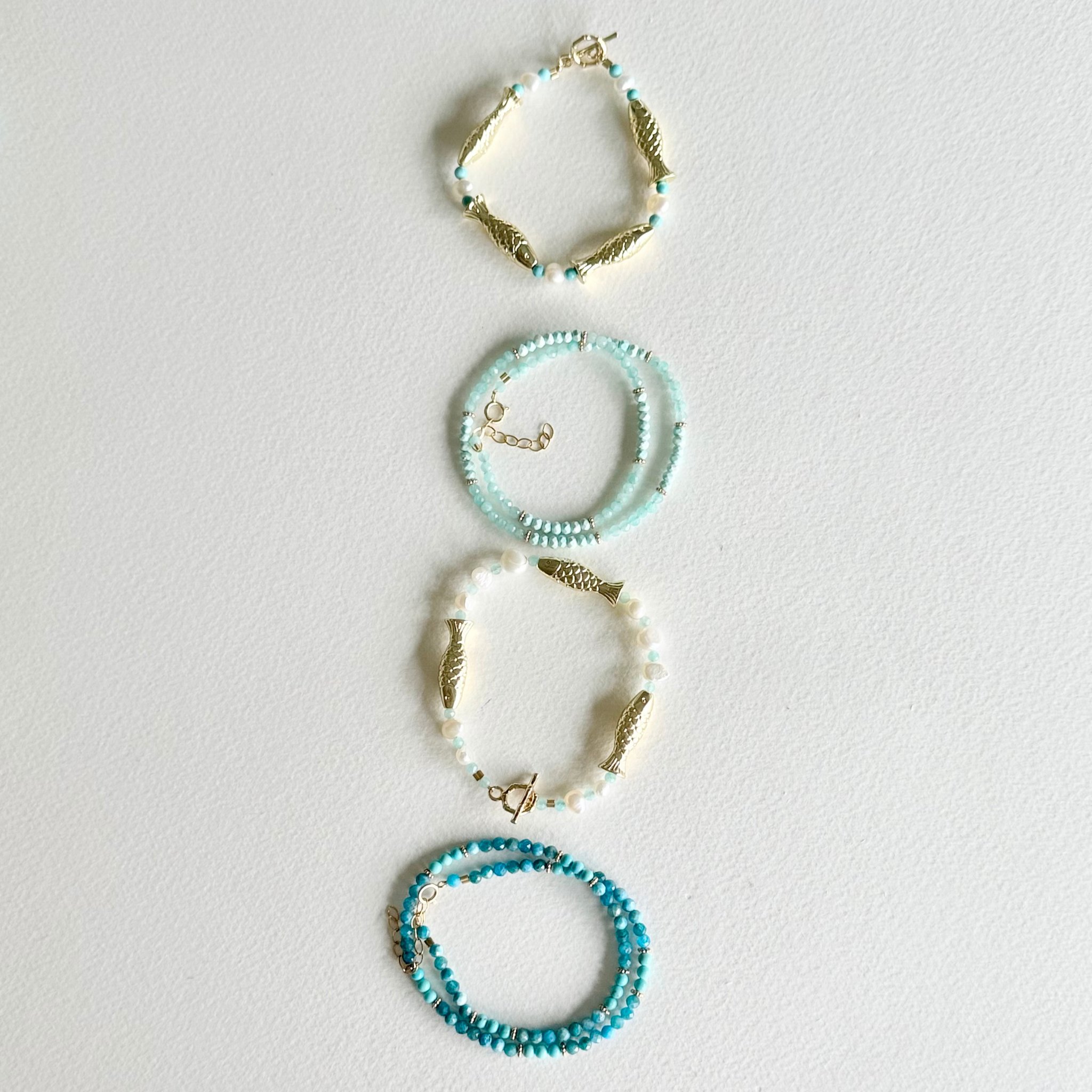 Set of four beaded bracelets on a light gray background