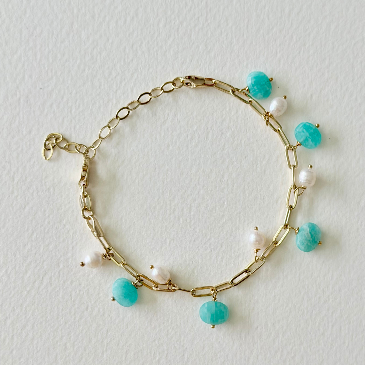 Gold bracelet with amazonite beads and pearls on a light background