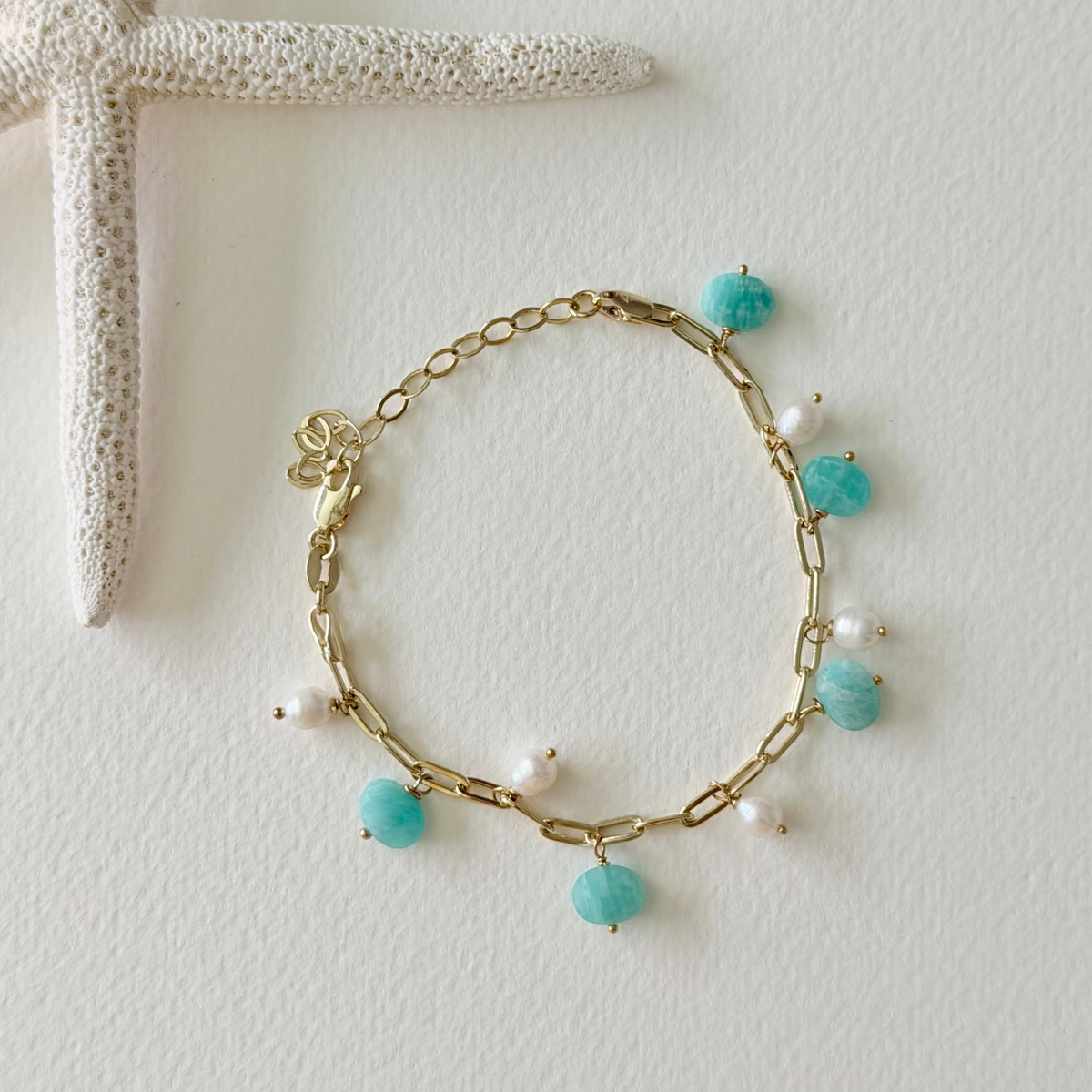 Gold chain bracelet with amazonite beads and pearls on a light background