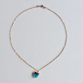gold necklace with a turquoise pendant on a light gray background