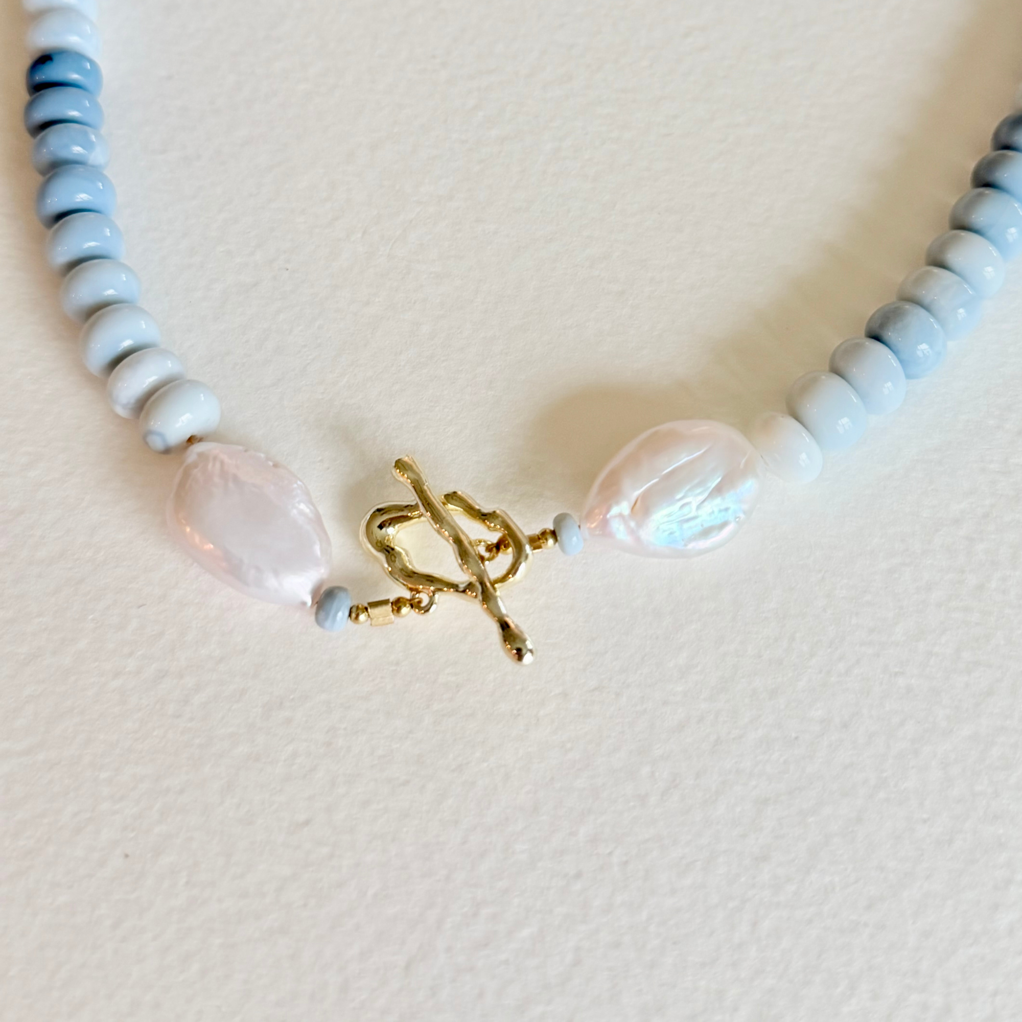 Necklace with blue, white, and gold beads on a light background