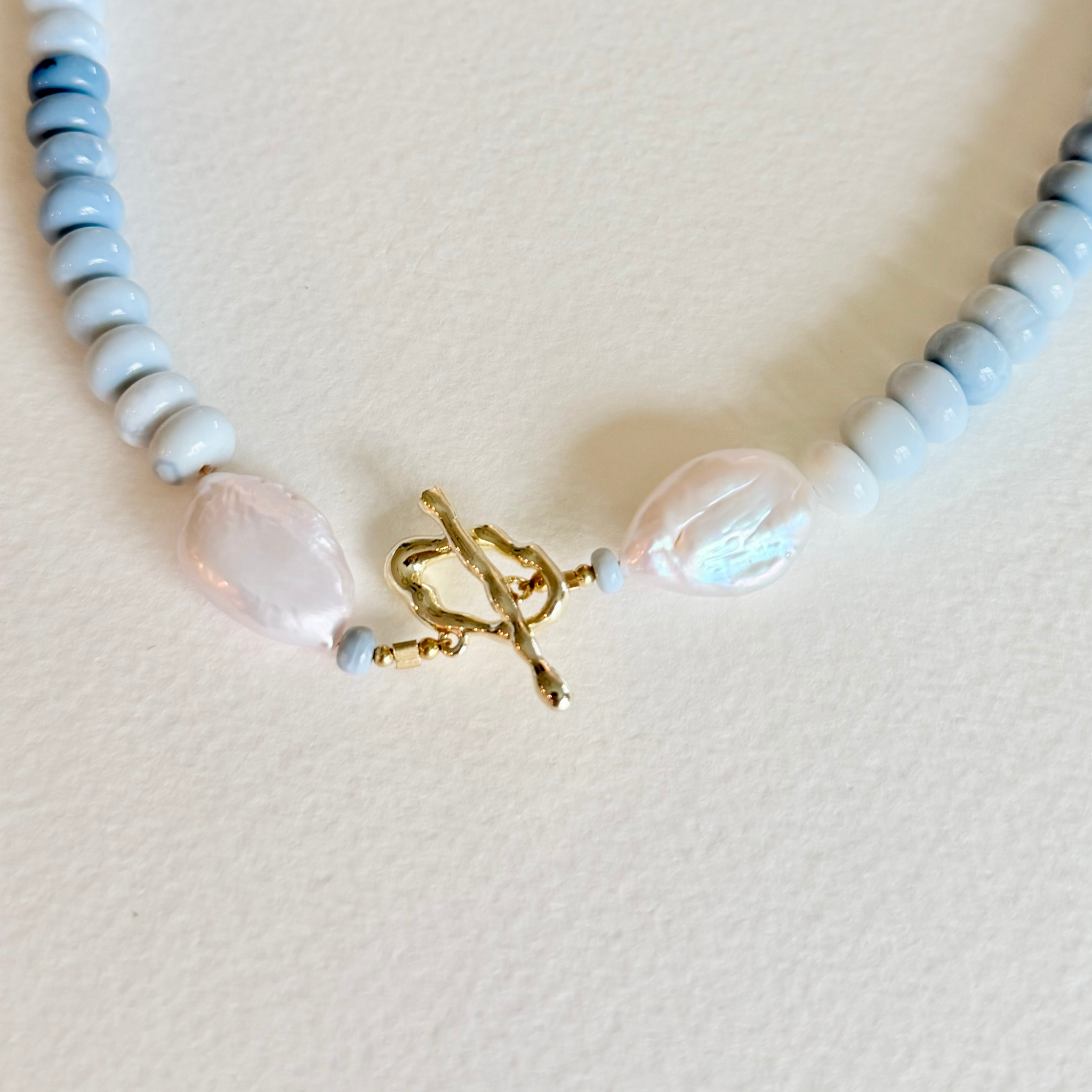 Necklace with blue, white, and gold beads on a light background