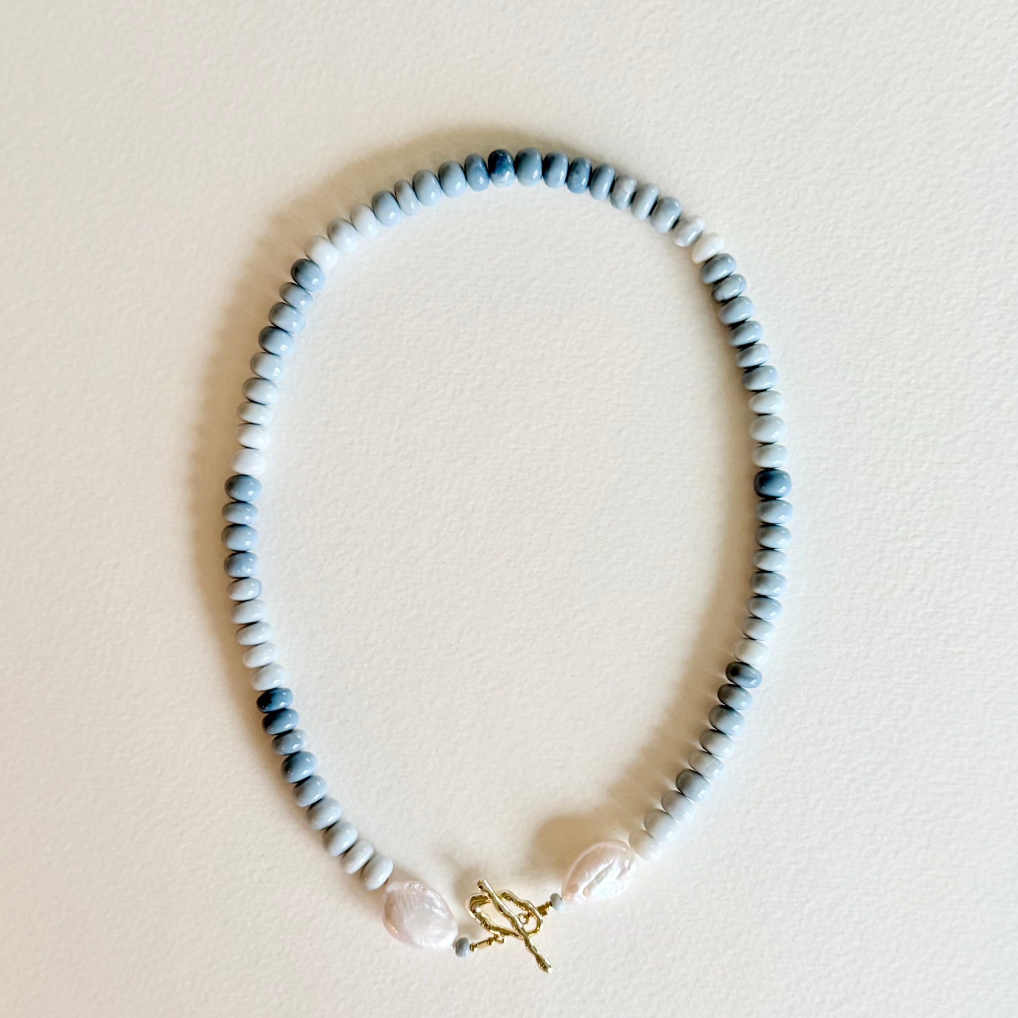 Necklace with blue beads and a gold charm on a beige background