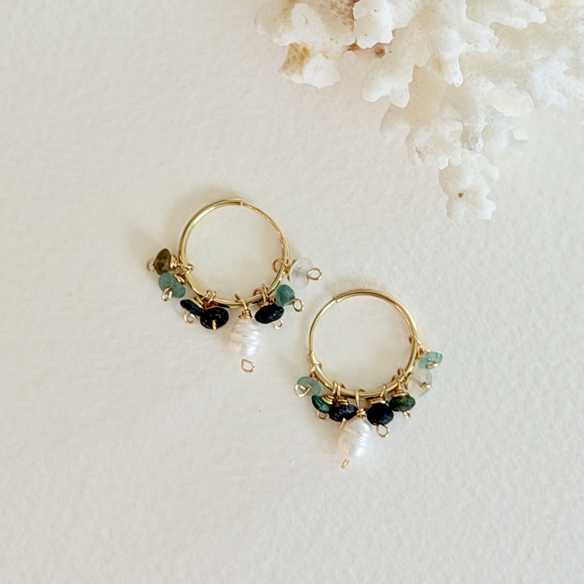 Gold hoop earrings with green and black beads on a white background
