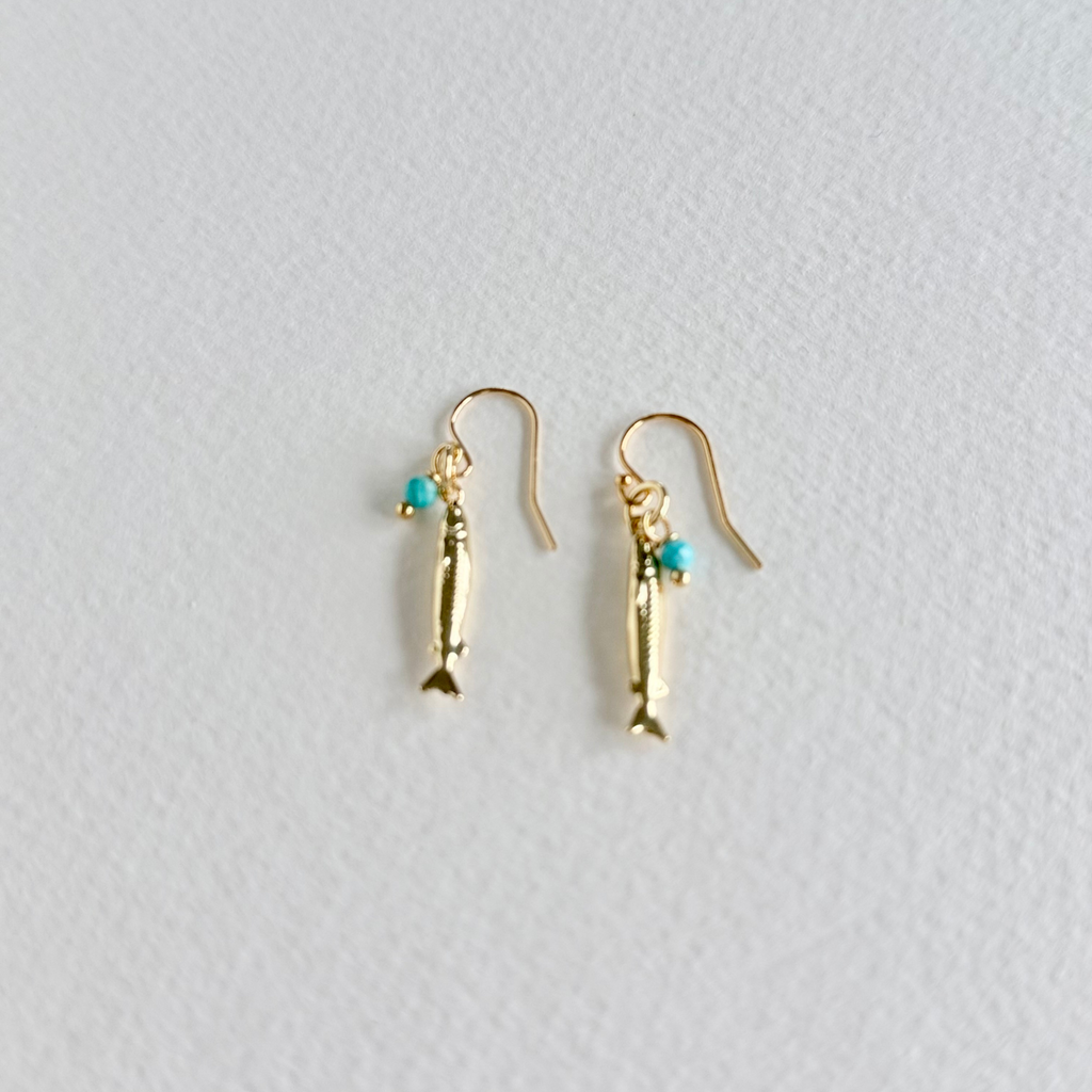Gold fish-shaped earrings with turquoise beads on a light gray background