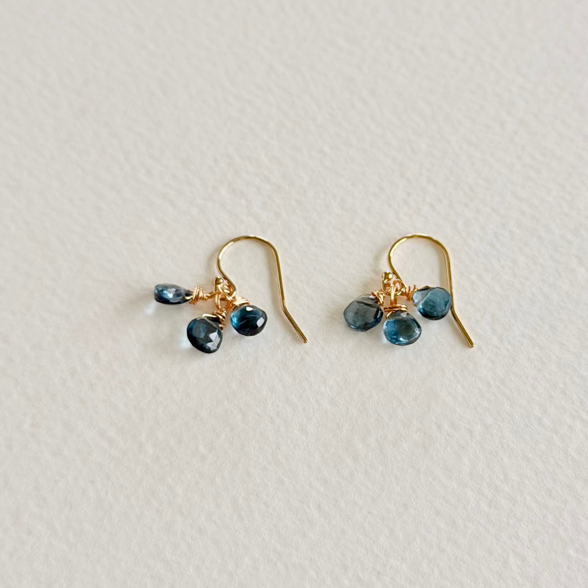 Gold earrings with blue gemstones on a light gray background