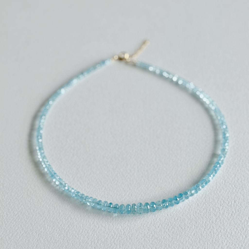 Light blue beaded necklace on a light gray background