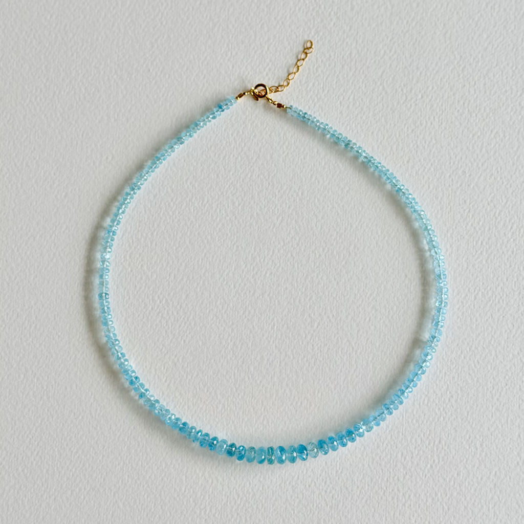 Blue beaded necklace on a light gray background