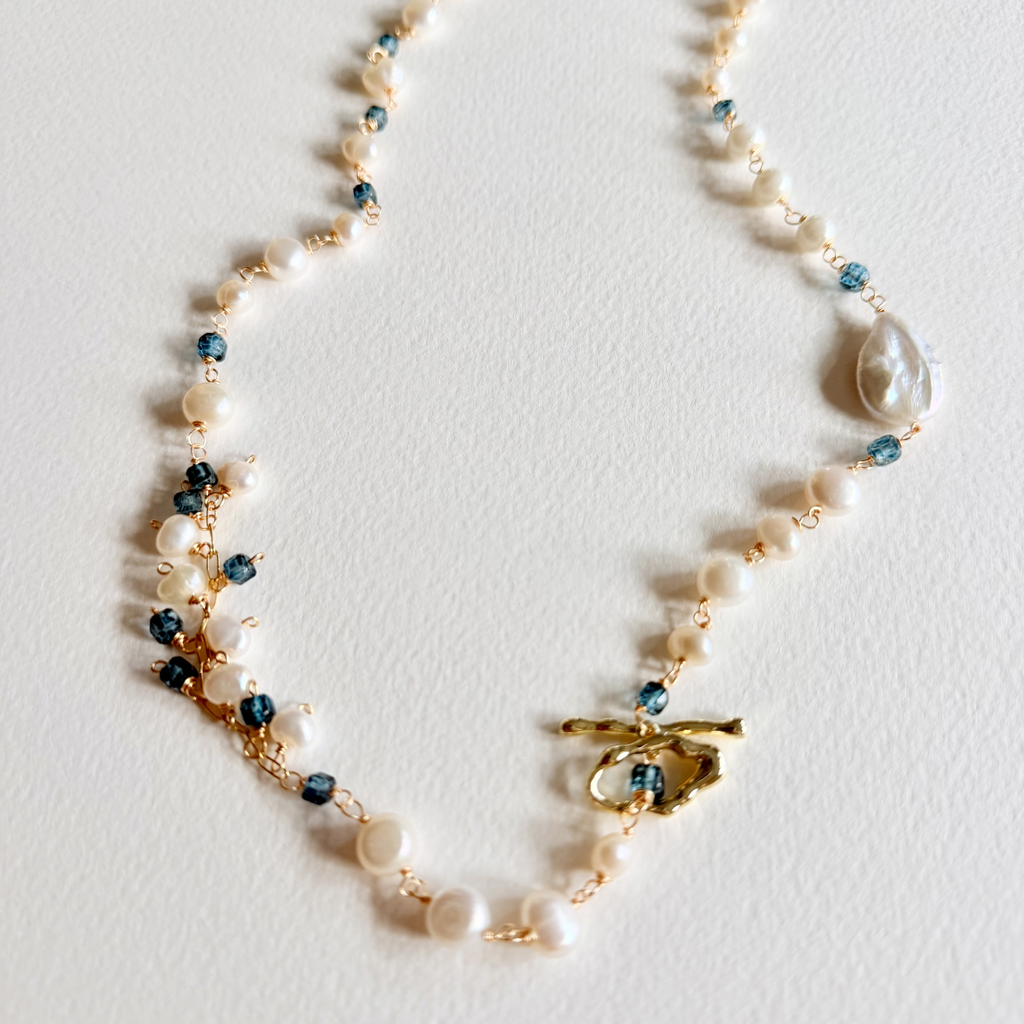 Necklace with pearls and blue beads on a white background
