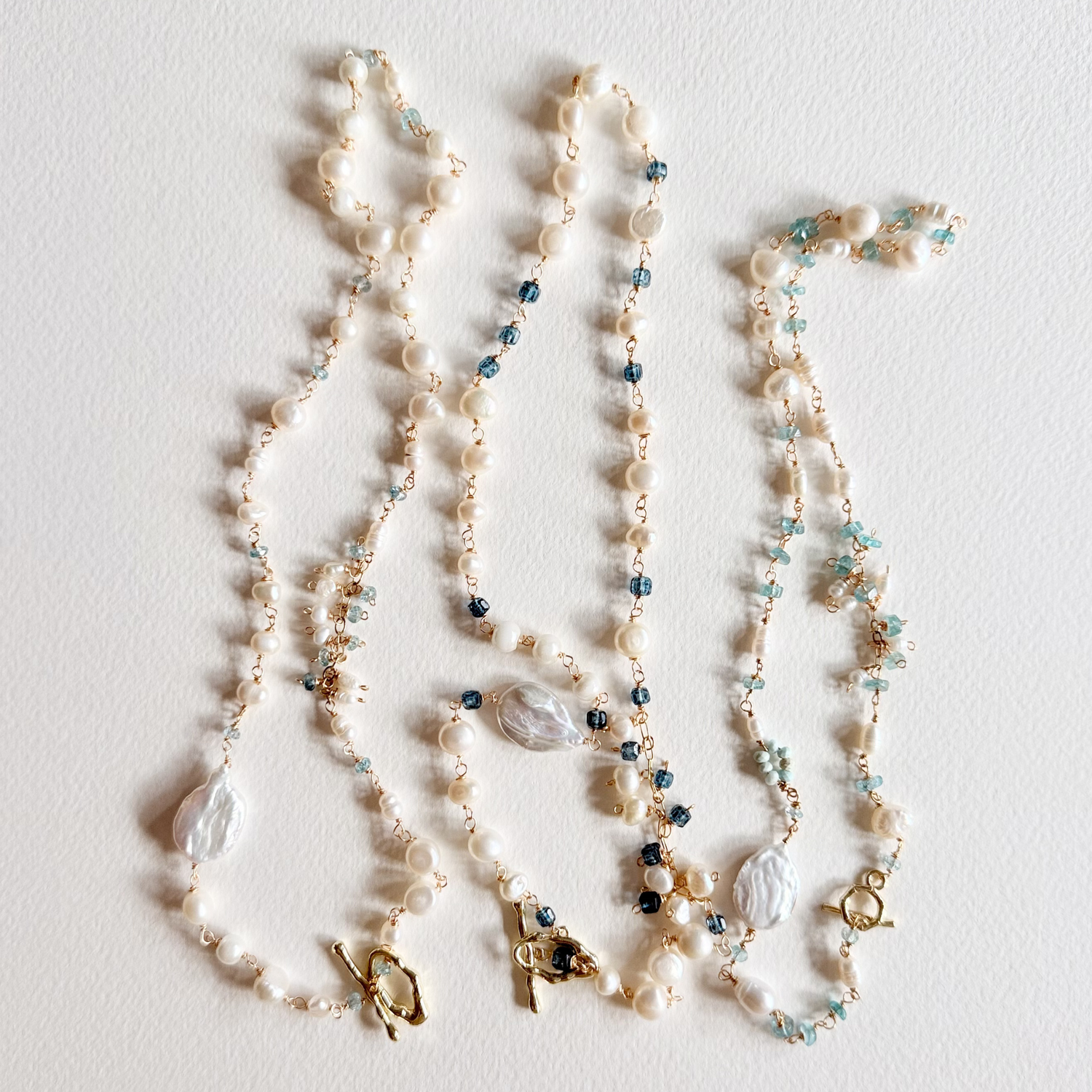 Three pearl necklaces with small beads on a light background