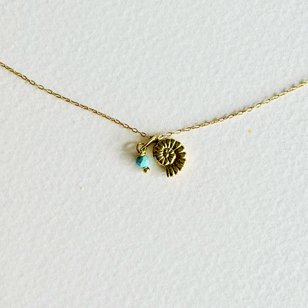 Gold necklace with a small pendant on a white background