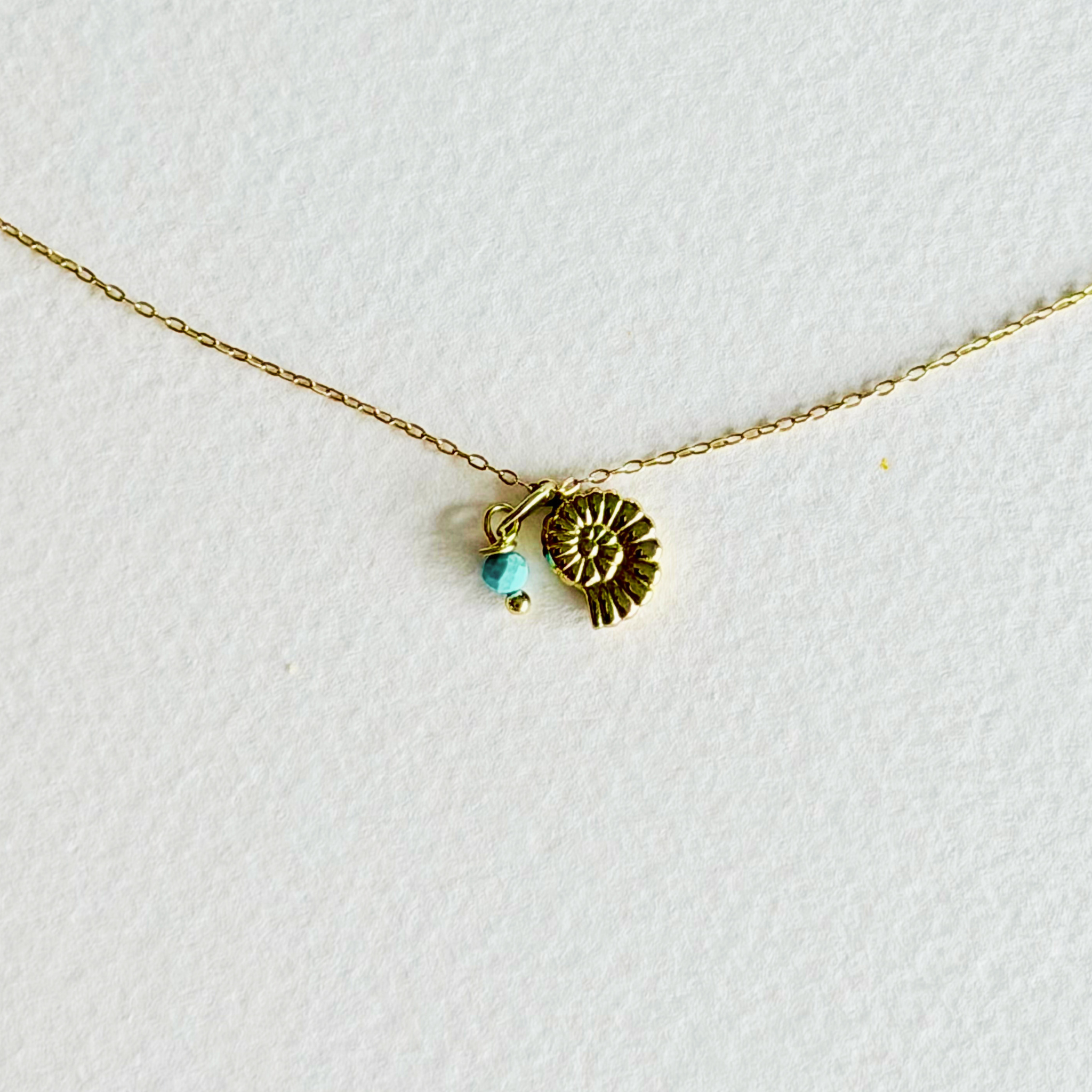 Gold necklace with a small pendant on a white background
