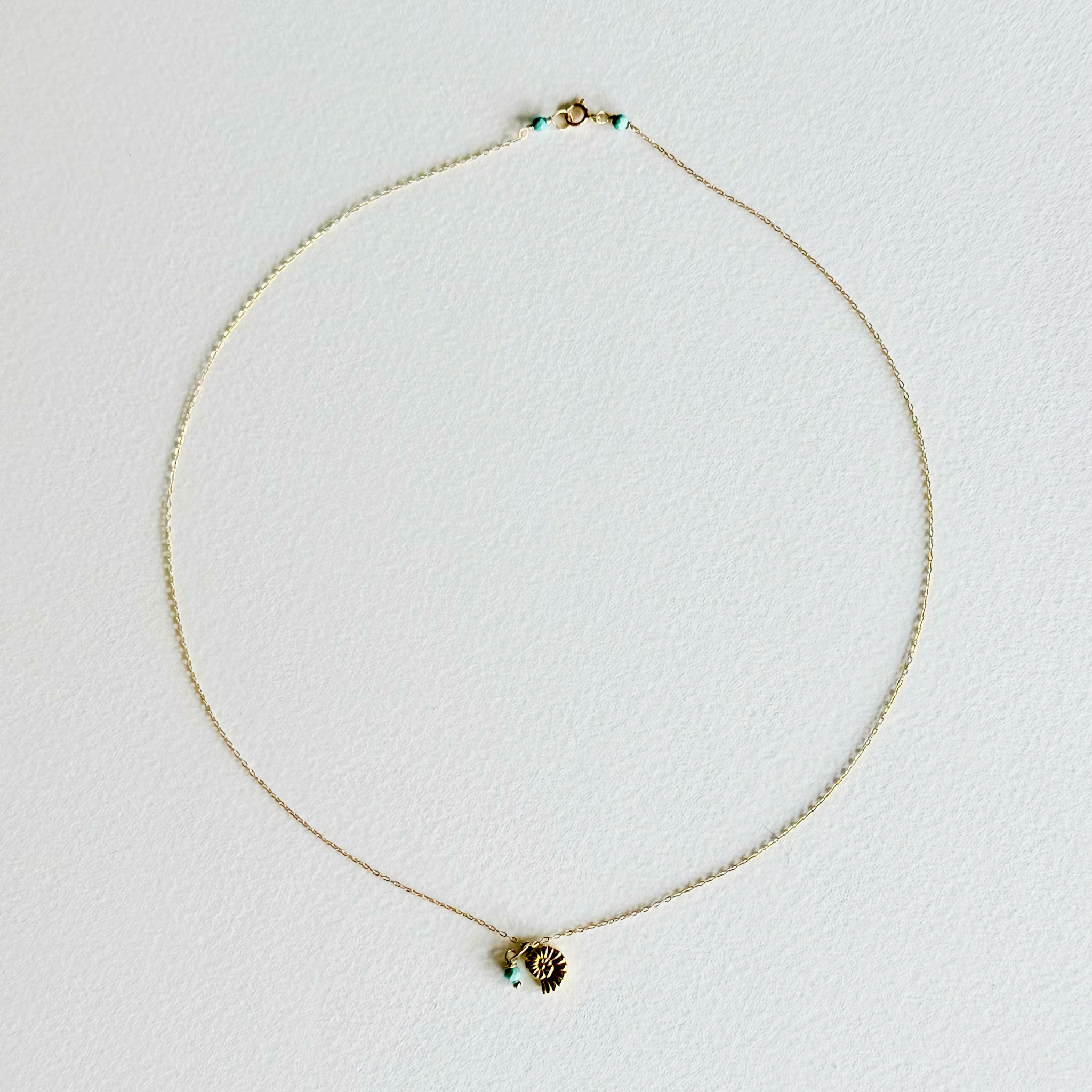 Gold necklace with a heart-shaped pendant on a light gray background