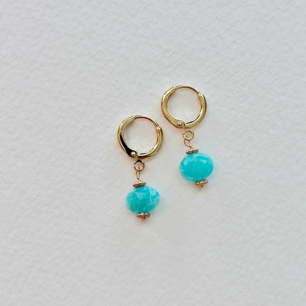 Gold hoop earrings with amazonite beads on a light gray background