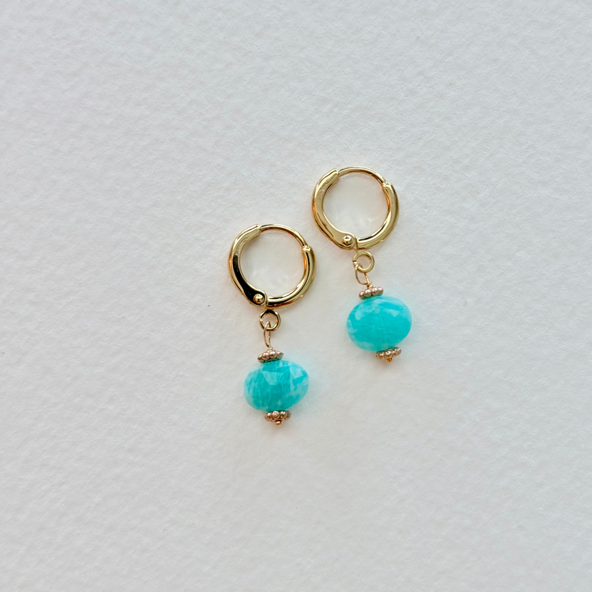 Gold hoop earrings with amazonite beads on a light gray background