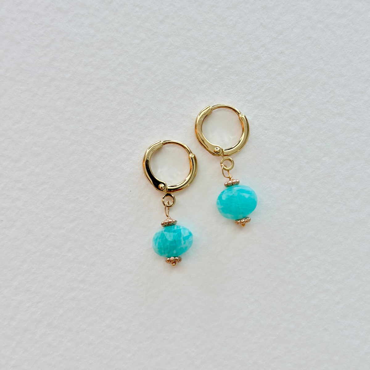 Gold hoop earrings with amazonite beads on a light gray background