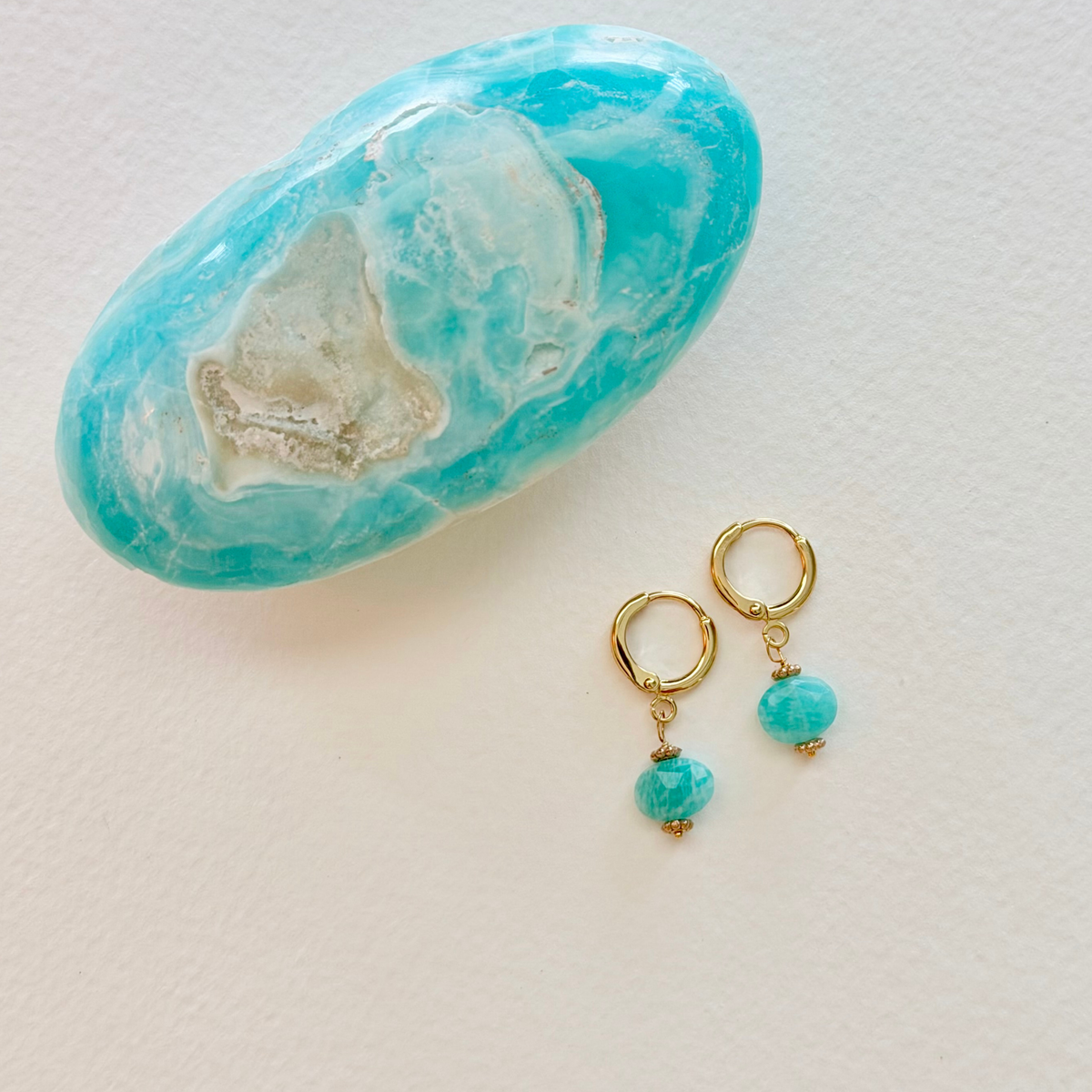 Gold hoop earrings with amazonite beads on a light background