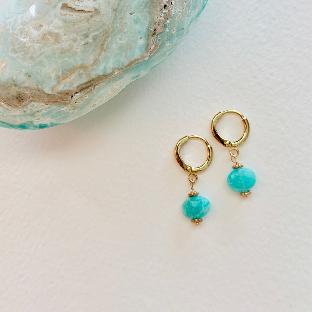 Gold hoop earrings with amazonite beads on a light background
