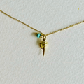 Gold necklace with a small green gemstone and gold charm on a white background