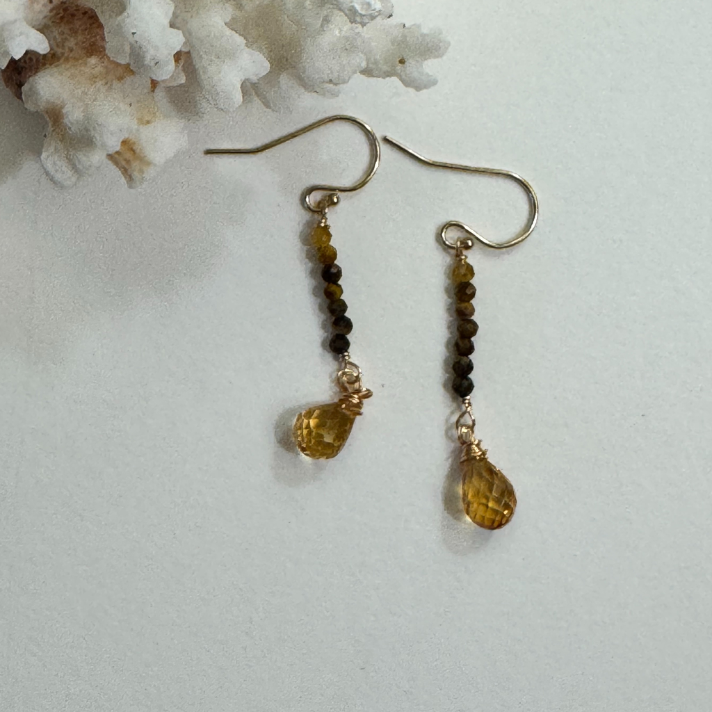 Genuine tiger eye and citrine gemstones in yellow and brown hues on 14k gold filled drop strand earrings displayed against a white background framed by white coral.