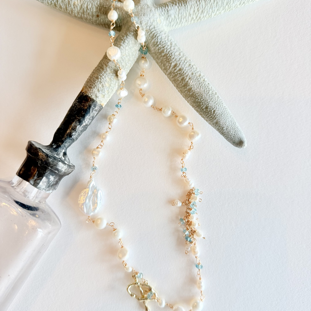 Pearl necklace with small beads on a white surface with a starfish