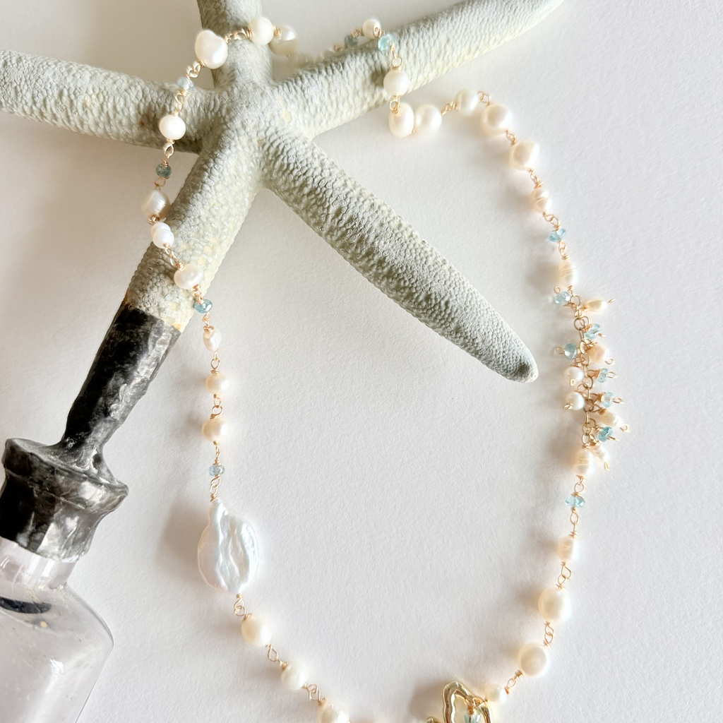 Pearl necklace with starfish and bottle on a light background