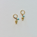 Gold hoop earrings with fish charms on a light gray background