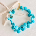 Turquoise beaded necklace with gold clasp on a white background