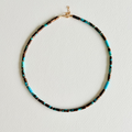 Necklace with turquoise and black beads on a light gray background