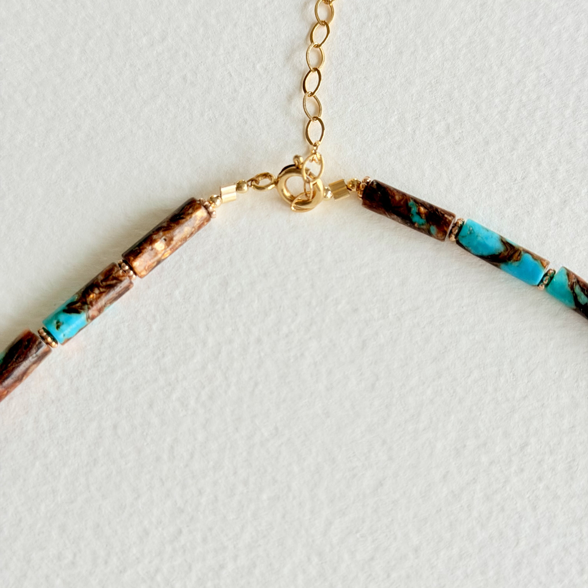 Necklace with brown and turquoise beads on a light gray background