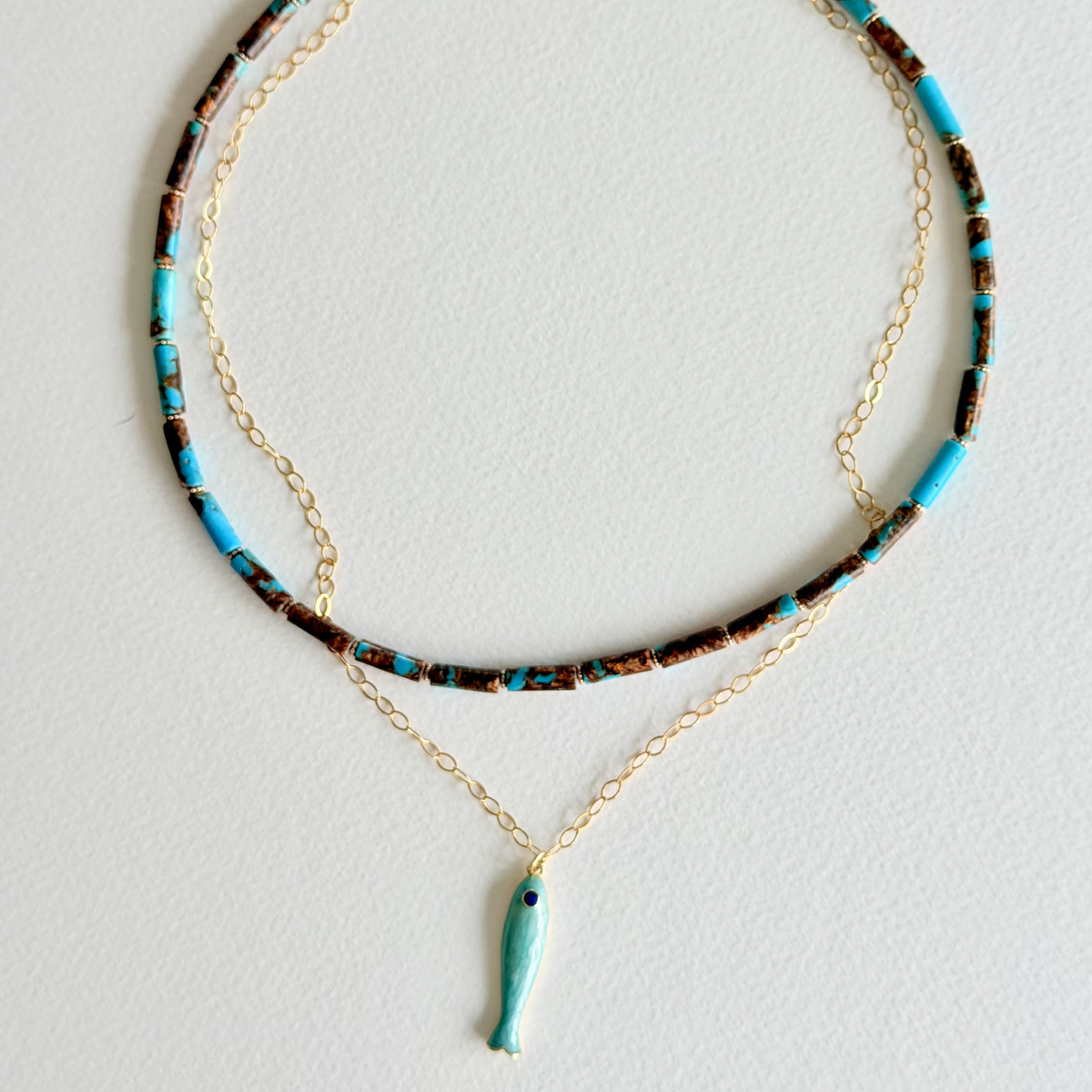 Necklace with turquoise fish pendant on a light gray background