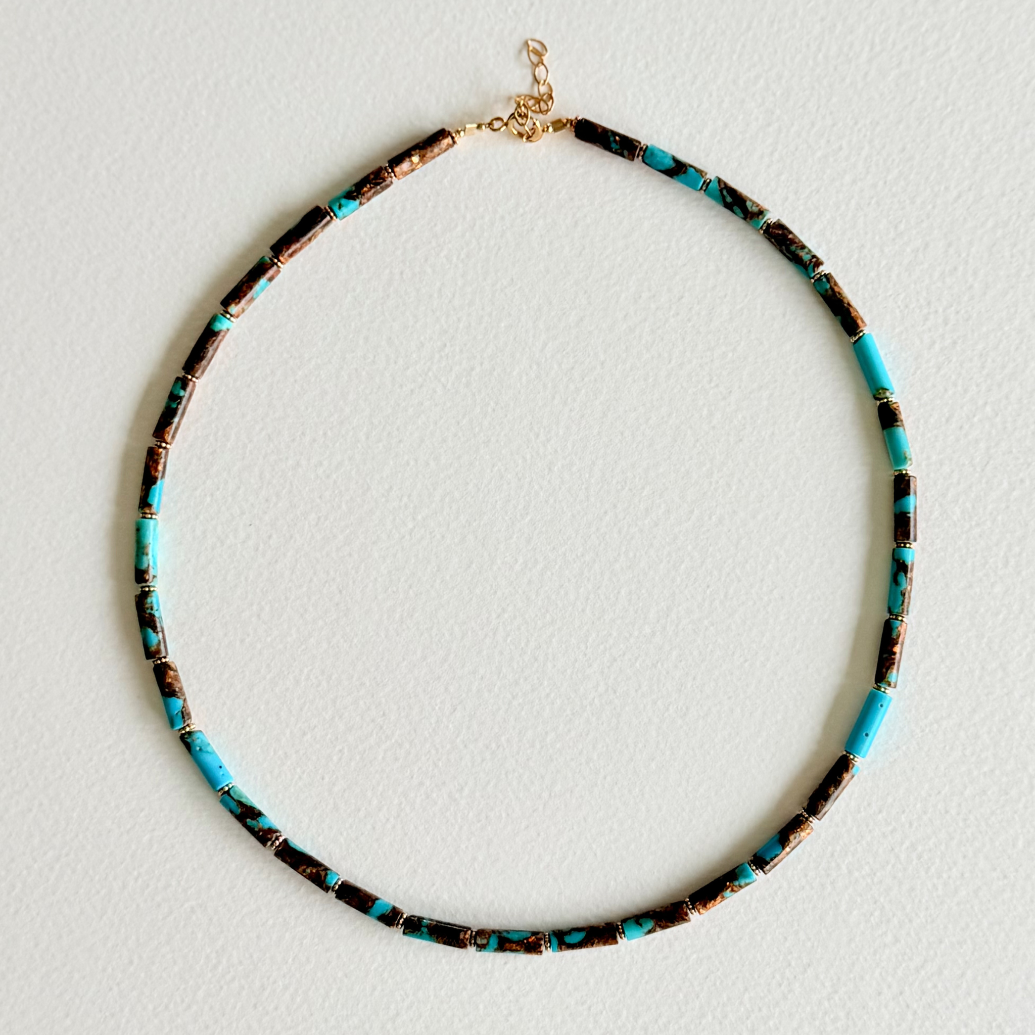 Necklace with turquoise and black beads on a light gray background