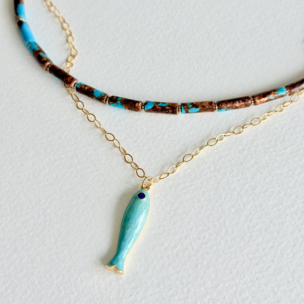 Necklace with a turquoise fish pendant on a light gray background
