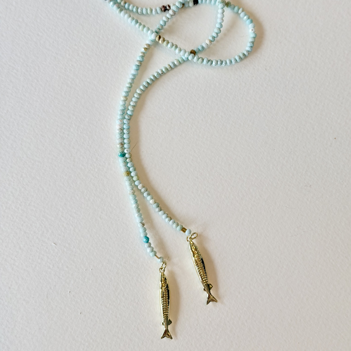 Necklace with fish-shaped pendants on a light pink background