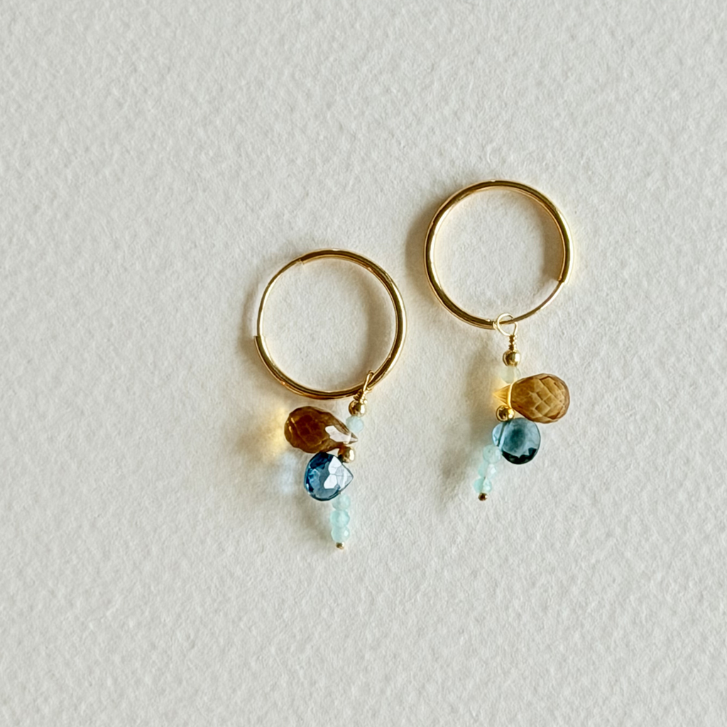Gold hoop earrings with colorful beads on a light gray background