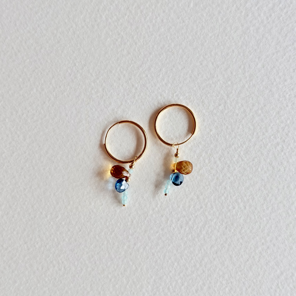 Gold hoop earrings with small beads on a light gray background